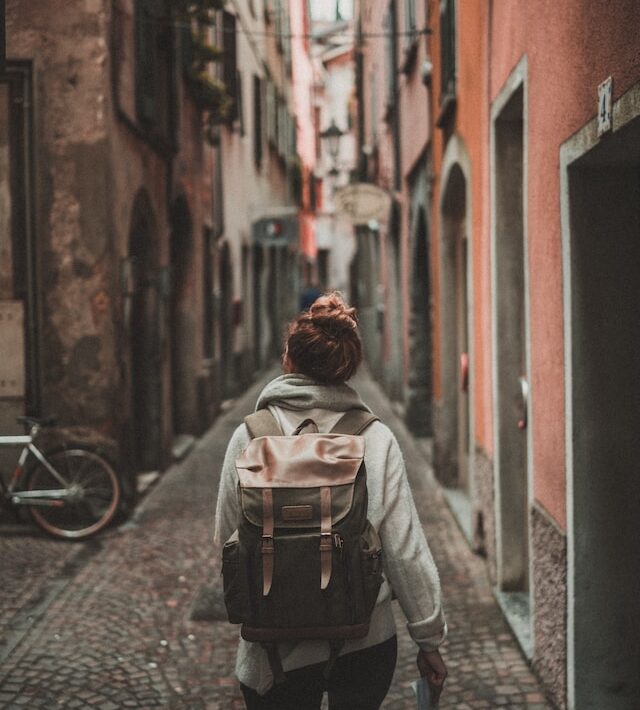 person walking through narrow road through buildings